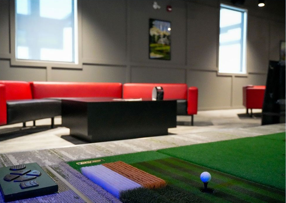 Red couches, black coffee tables in background. Golfzon tee area in foreground. Shanks Brandon.